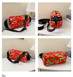 Detail view of red floral quilted cylinder bag with branded wide strap on white table