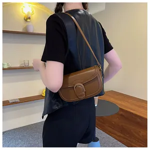 Vue latérale du sac besace en cuir marron caramel porté par un mannequin en intérieur