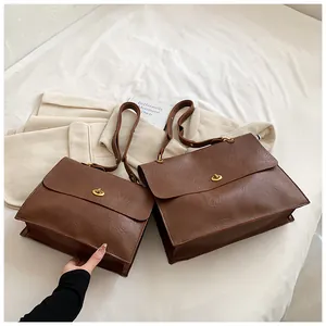 Detailed view of brown PU leather handbags with elegant gold twist-lock closure in two sizes