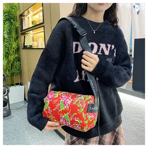 Close-up of red floral quilted crossbody bag with adjustable nylon shoulder strap