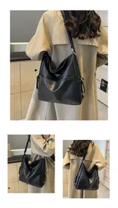 Detail of black faux leather tote bag with gold hardware and adjustable strap on a model
