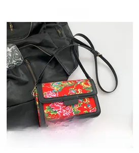 Close-up of red crossbody bag with traditional Chinese peony pattern and black strap