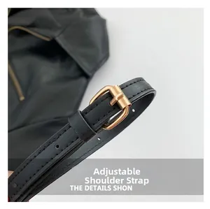 Detail of adjustable shoulder strap with golden metal buckle on black leather crossbody bag