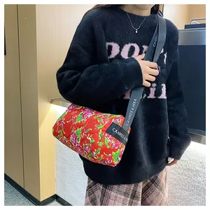 Detailed shot of a red floral quilted cylinder bag with branded logo wide strap