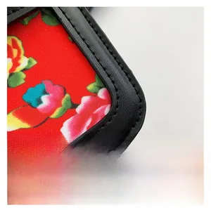 Detail of black lychee leather piping and traditional red floral fabric lining on bag