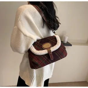 Detail of red-brown checkered wool bag with faux shearling trim and brown leather strap