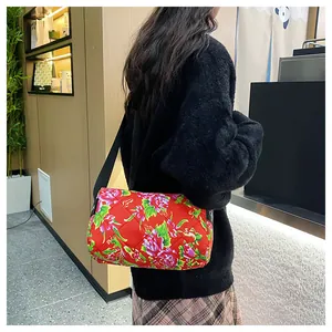 Detail of red floral quilted cylinder bag with traditional peony pattern and wide black strap