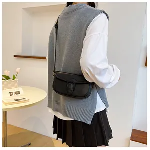 Détail d'un sac besace noir vintage avec boucle fer à cheval porté à l'épaule
