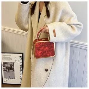 Detail view of a vintage dark red marble box bag with gold frame and chain strap