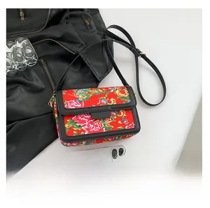 Detail of red floral crossbody bag showing the peony pattern and adjustable black strap