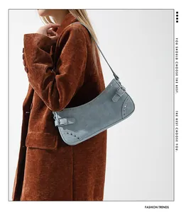 Gros plan d'un sac baguette en denim bleu clair avec boucles argentées porté par un mannequin