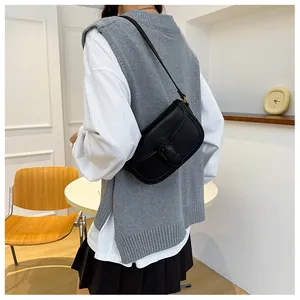Sacoche noire chic portée avec un gilet en maille minimaliste et une chemise blanche