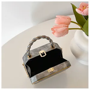 Detailed view of grey evening clutch bag with golden metal frame and chain strap