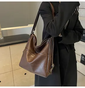 Detail showing the glossy dark brown leather texture and stitching of the large tote bag