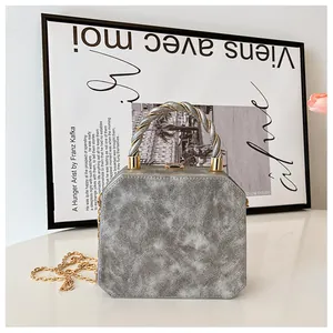 Detail of a hexagonal silver marble clutch with gold metal handle and chain strap