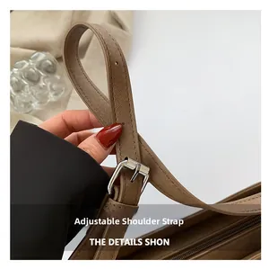 Détail de la bandoulière réglable avec boucle argentée sur un sac en cuir à grain croisé