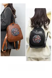 Detail of vintage backpacks in brown and black with ethnic embroidery and adjustable straps