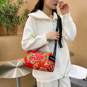 Quilted cylinder crossbody bag with traditional red floral pattern and adjustable strap