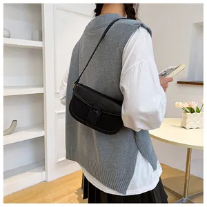 Sac à rabat en cuir noir classique porté avec un gilet gris et une chemise blanche chic