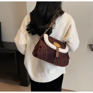 Detail of plaid shoulder bag with faux fur trim and gold hardware on white sweater
