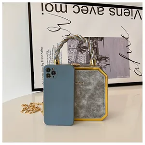 Detail of grey marble box bag with golden metal frame and woven two-tone handle