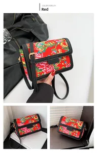 Detail of red floral crossbody bag with phoenix pattern and black leather trim