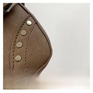 Détail du sac à main en cuir marron grainé avec rivets argentés et surpiqûres précises