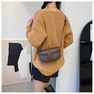 Détail du sac de selle en cuir marron avec fermoir fer à cheval sur un mannequin