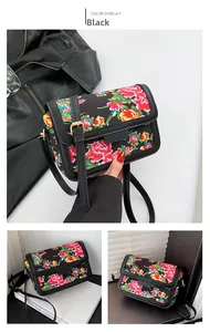 Detail of black crossbody bag with red peony print and golden metal buckle decoration