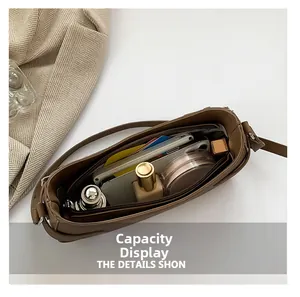 Vue intérieure du sac terre d'ombre avec compartiment zippé et accessoires du quotidien