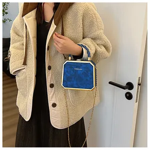 Detail of navy blue octagonal crossbody bag with gold frame and twisted rope handle