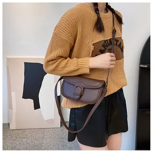 Détail d'un sac besace marron foncé mat avec grande boucle décorative et bandoulière réglable