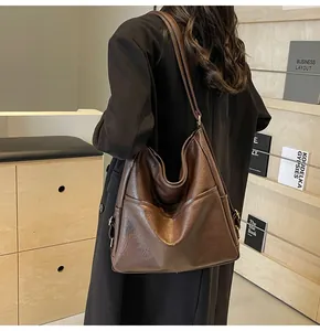 Close-up of the vintage brown leather texture and decorative side buckle on a large tote bag