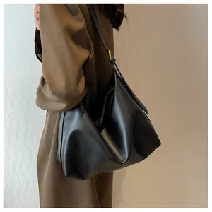 Detail of a black matte faux leather tote bag with a golden metal buckle on a shoulder strap