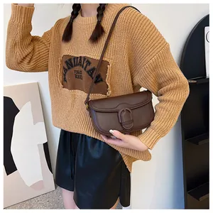 Détail d'un sac à bandoulière marron vintage avec boucle fer à cheval sur un mannequin