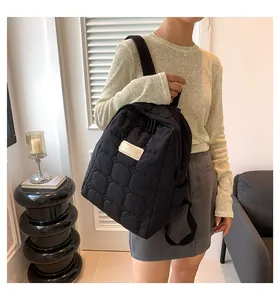 Detail view of a black quilted puffer backpack with soft nylon fabric and a chic mini patch