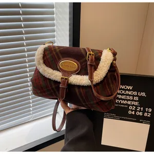 Detail of red and green plaid shoulder bag with white faux shearling trim and gold buckle