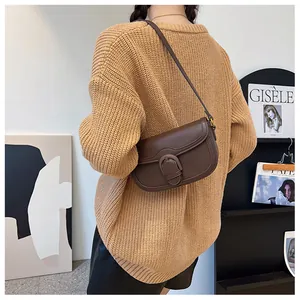 Détail du sac selle en cuir marron foncé avec boucle vintage et texture de haute qualité
