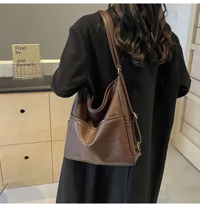 Close-up of brown faux leather tote bag showing side pocket and metal strap buckle
