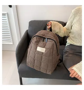 Detail view of brown quilted backpack with hexagonal patterns and white logo patch