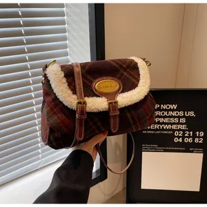 Detail of red and green plaid wool crossbody bag with white fleece trim and leather strap