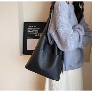 Detail of black pebbled leather tote bag shown on model for realistic drape and scale