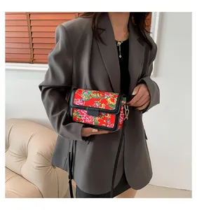 Detail view of ethnic red floral crossbody bag worn with a stylish grey blazer suit