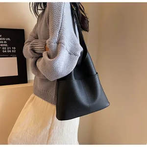 Side view of a black lychee texture leather bucket bag with vertical stitching detail