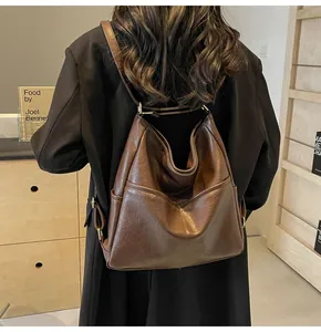 Detail of soft brown leather backpack with textured surface and gold metal buckle
