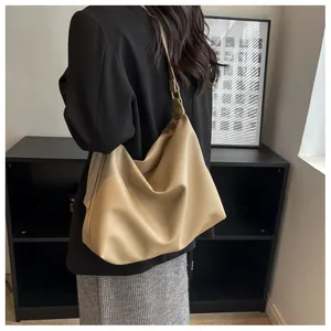 Detail of soft khaki faux leather tote bag with gold buckle on shoulder strap worn by model