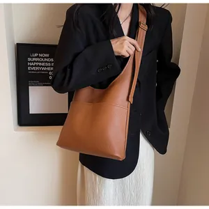Close-up of brown pebbled leather shoulder bag with fine stitching and retro copper buckle