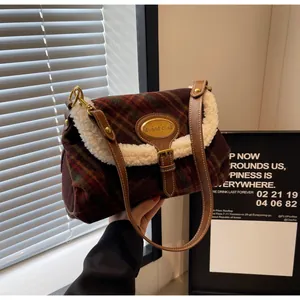 Detail of red and brown plaid bag featuring plush faux shearling trim and gold metal clasp