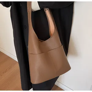 Detail of brown leather bucket bag showing lychee grain texture and front slip pocket
