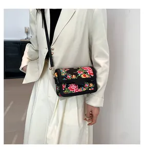 Detail of floral crossbody bag with gold hardware worn on elegant cream blazer